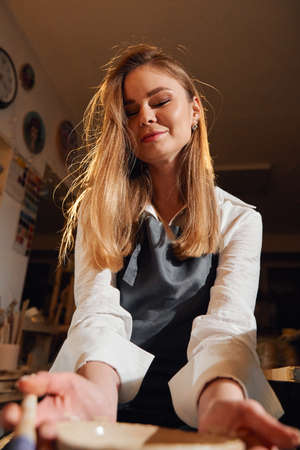 Portrait of a girl in a pottery workshop. Beautiful brunette at the potters wheel.の写真素材