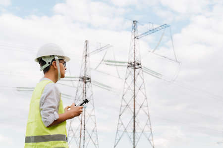 A young Engineer examines the high-voltage tower with a drone.の写真素材