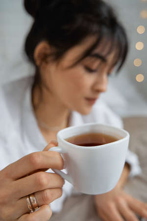 Portrait of smiling happy cheerful beautiful pretty asian woman relaxing reading a book enjoy of rest.Young student girl studying with book in holiday morning vacation on bed at home with copy spaceの写真素材