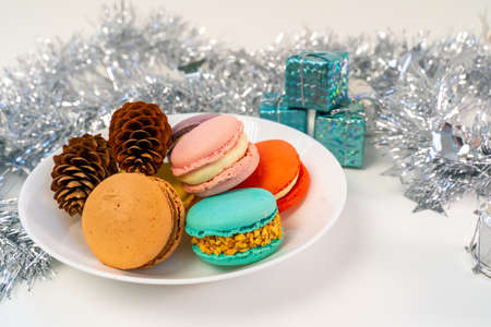 Multicolored French cookies in a wooden plate on a background of tinsel.の写真素材