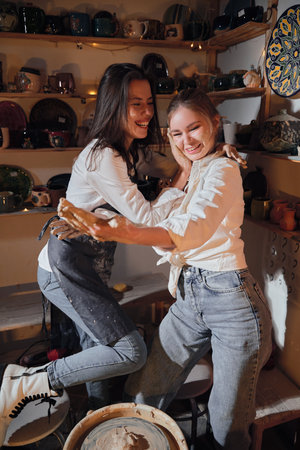 Two beautiful girls in a pottery workshop in a cozy studio, love and relationship.の写真素材