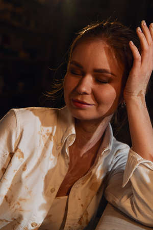 Portrait of a girl in a white shirt in a pottery workshop. Her shirt is smeared with clay.の写真素材