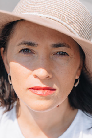 A middle-aged woman in a summer hat looks at the camera. Portrait of a girl.の写真素材