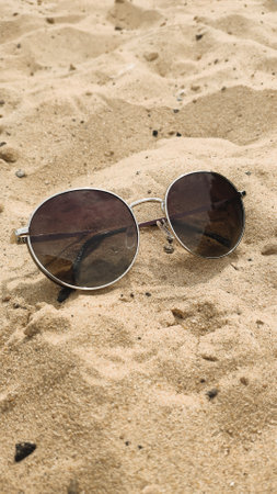 Top view of sunglasses on the beach. Sunglasses in a metal frame on the sand.の写真素材