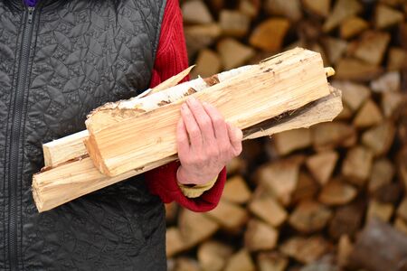 Old woman with firewood in the hands in the village.の写真素材