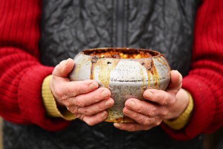 old woman with old iron pot with porridge in her hands. traditional russian food.の写真素材