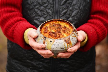 old woman with old iron pot with porridge in her hands. traditional russian food.の写真素材