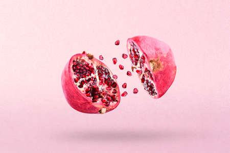 Pomegranate in flight burst. Cut half pomegranate flying in the air. Pomegranate fruit explosionの写真素材