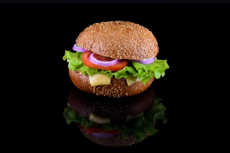 Fresh tasty burger isolated on black background. Tasty and appetizing cheeseburger. Vegetarian burgerの写真素材