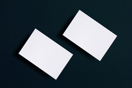 Mock up of two horizontal white business cards at black textured paper background.の写真素材