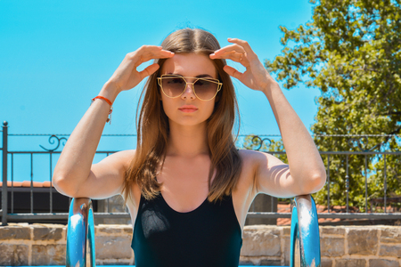 Beautiful Tanned skin Slim Girl woman in black swimsuit fashion make up and retro sun glasses, Blue sky holiday vacation styleの写真素材