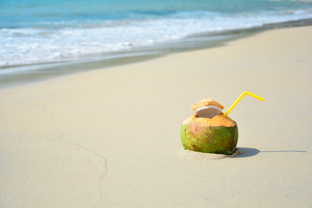 Coconut with drinking straw on beach at the sea. Tropical travel concept with copy spaceの写真素材