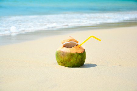 Coconut with drinking straw on beach at the sea. Tropical travel concept with copy spaceの写真素材