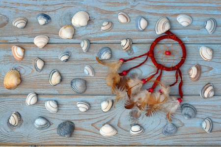 Bordeaux dark red dream catcher with feathers on old wooden background with sea shellsの写真素材
