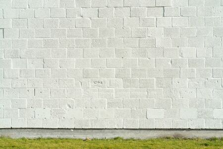 white painted bricks wall with empty copy space with green grassの写真素材