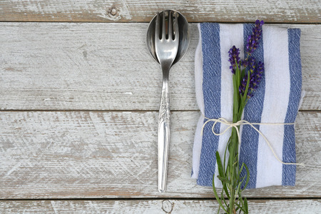 silver cutlery on a blue white napkin with lavender decoration and empty copyspace in vintage...