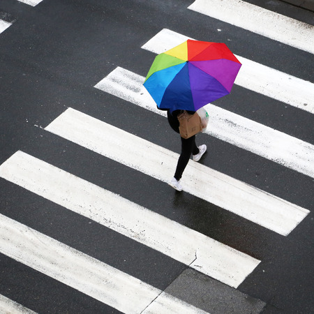 Woman crossing the zebra with umbrellaの写真素材