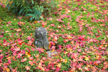 Small smile Jizo stone sculpture on the moss land covered by red maple leaves in autumn, at Enkoji Temple, Kyoto, Japanのeditorial素材
