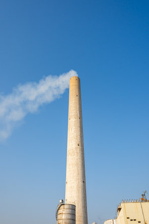 A huge chimney of a modern industrial factory against blue skyの写真素材