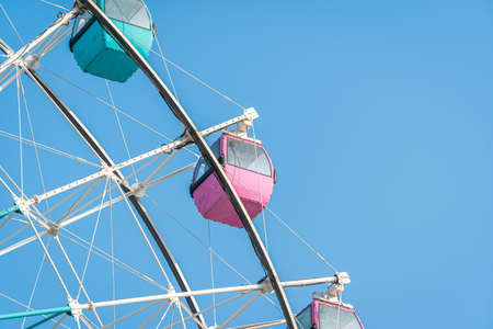 Colorful ferris wheel in an amusement park against blue skyの写真素材