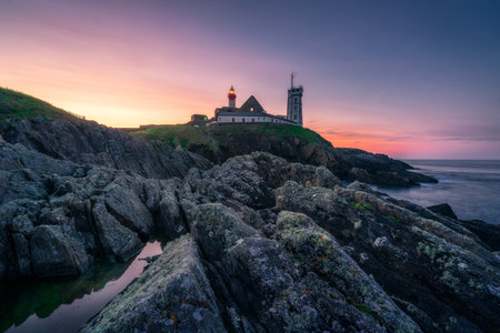 Saint-Mathieu Lighthouse at sunrise, with cliff rocks on foreground, on Pointe Saint-Mathieu in Plougonvelin, Brest, Franceの写真素材