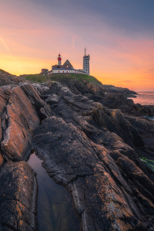 Saint-Mathieu Lighthouse at sunrise, with cliff rocks on foreground, on Pointe Saint-Mathieu in Plougonvelin, Brest, Franceの写真素材