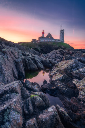 Saint-Mathieu Lighthouse at sunrise, with cliff rocks on foreground, on Pointe Saint-Mathieu in Plougonvelin, Brest, Franceの写真素材