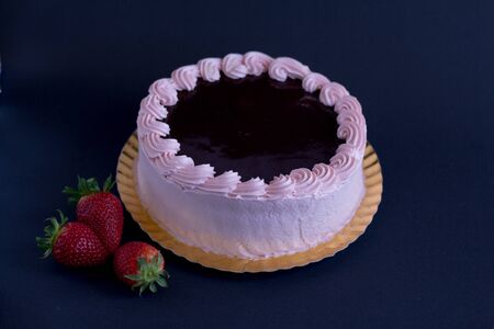 strawberry and chocolate cake cover with pink cream and fresh strawberry in black background. Top...