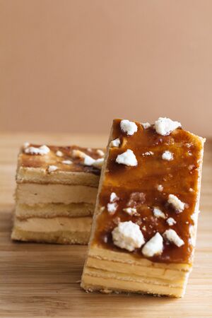 Two pieces of cream and sponge cake over wood pieces with brown background