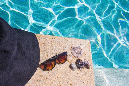 black hat, sunglasses and seashells to the edge of poolの写真素材