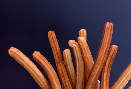 Churros with sugar on black background. top view