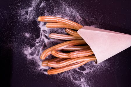 Churros sticks fresh hot with sugar in paper bag on dark backgroundの写真素材