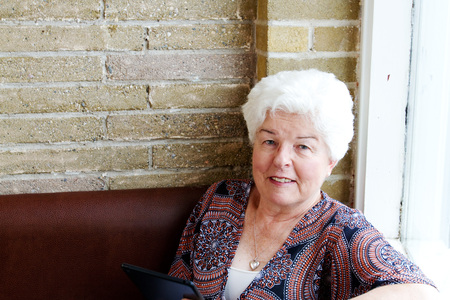 Senior lady reading tablet in coffee shop
