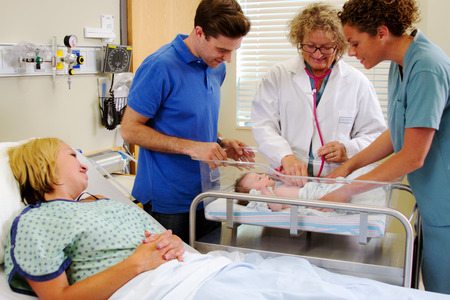 Health team examining baby as parents watch