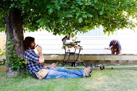 Carpenter enjoying coffee in shade of tree