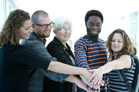 Four students and tutor with hands together