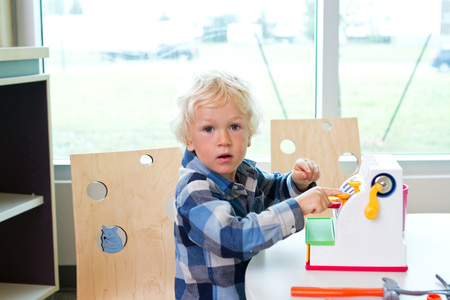 Boy playing with cash register at libraryの写真素材