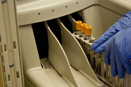 Technician inserting blood tubes into machine for analysis