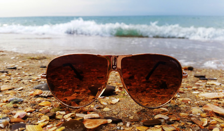 Sunglasses on the sand beach. Waves background.の写真素材