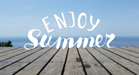 Hand written lettering composition.Phrase Enjoy Summer. Wooden pier and the sea.の写真素材