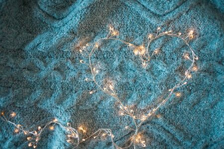 Garland heart with glowing lights in the background of a fluffy grey blanket, the comfort of home, the Christmas atmosphere.の写真素材