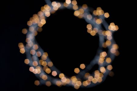 Round frame of luminous garland unfocused, free space for your design in the center. black backgroundの写真素材