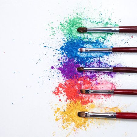 Bright eye shadows in different colors of the rainbow and brushes for cosmetics on a white background.. Creative makeup, conceptの写真素材