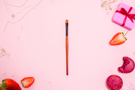 Cute pink flat lay, with a fine makeup brush in the center . Glamorous style, elements cosmetics and sweets on frameの写真素材