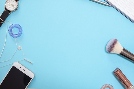 flat lay template in a modern business style on a blue background, contents of women's handbag, phone, cosmetics and watches, free space in the centerの写真素材