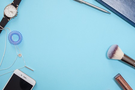 flat lay template in a modern business style on a blue background, contents of women's handbag, phone, cosmetics and watches, free space in the centerの写真素材
