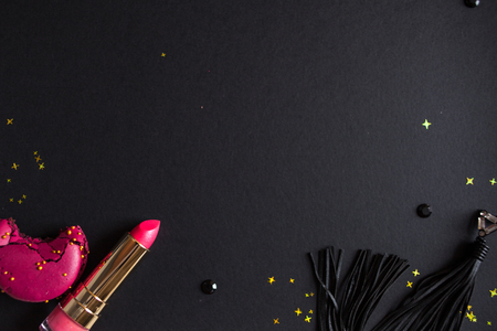 flat lay template, in glamorous chic style, black background, scarlet lipstick and gold sequins. free space in the centerの写真素材