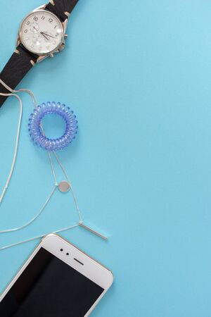 flat lay template in a modern business style on a blue background, contents of women's handbag, phone, cosmetics and watchesの写真素材
