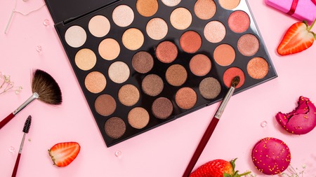 Eyeshadows and correctors, a large palette of make-up artist, Cute pink flat lay. Glamorous style, elements cosmetics and sweets on frameの写真素材