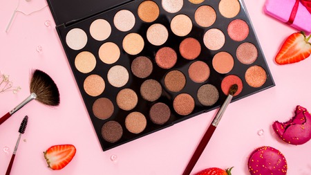 set of different eyeshadow in the Nude palette, Cute pink flat lay. Glamorous style, elements cosmetics and sweets on frameの写真素材